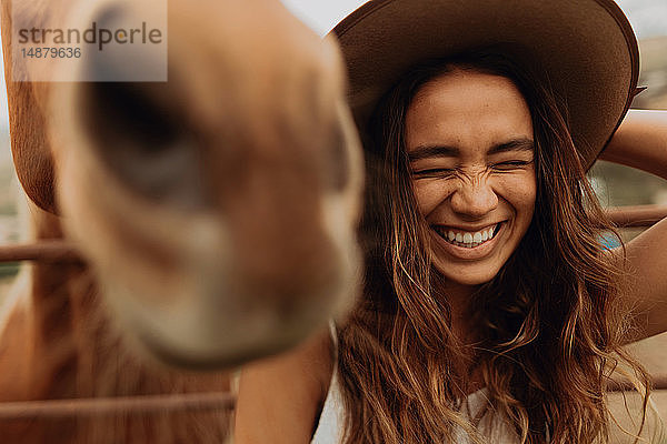 Junge Frau mit Filzhut lacht neben dem Pferd  Jalama  Kalifornien  USA