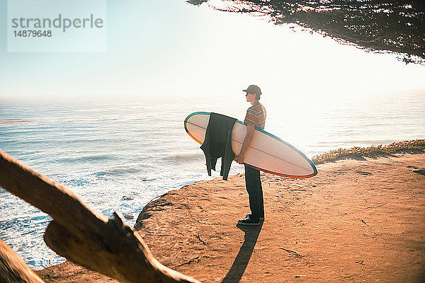 Junger Mann mit Surfbrett am Strand  Morro Bay  Kalifornien  Vereinigte Staaten