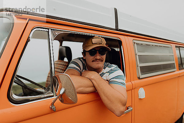 Junger Mann lehnt sich aus dem Fenster eines Wohnmobils  Porträt  Jalama  Kalifornien  USA