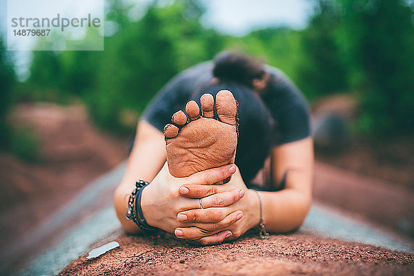 Frau sitzt und beugt sich auf einem Felsen vor