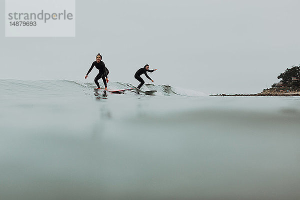 Junges Surferpaar beim Surfen auf ruhiger  nebliger See  Ventura  Kalifornien  USA