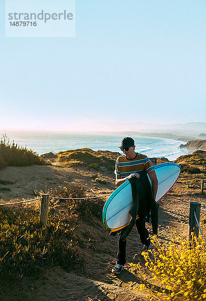 Junger Mann mit Surfbrett am Strand  Morro Bay  Kalifornien  Vereinigte Staaten