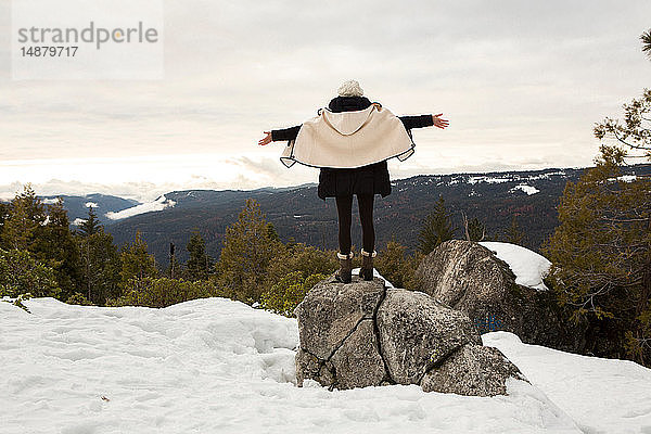 Junge Frau steht auf Fels auf schneebedecktem Berg  Rückansicht  Twain Harte  Kalifornien  USA