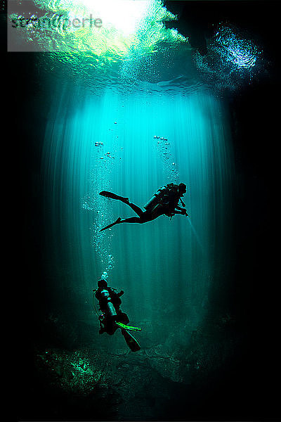 Unterwasseransicht männlicher und weiblicher Taucher bei der Erkundung der Cenote The Pit   Tulum  Quintana Roo  Mexiko