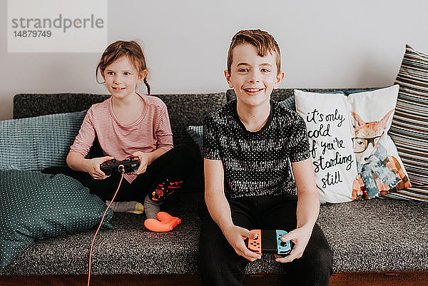 Kinder spielen Videospiel auf der Couch