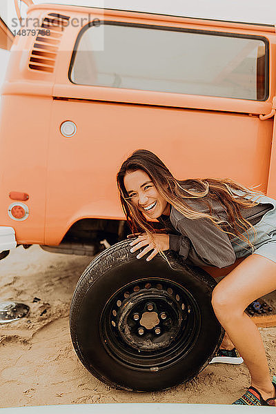 Junge Frau beim Reifenwechsel an einem Wohnmobil am Strand  Portrait  Jalama  Kalifornien  USA