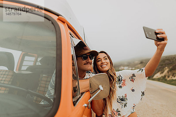 Junges Paar am Straßenrand in einem Wohnmobil beim Smartphone-Selfie  Porträt  Jalama  Kalifornien  USA