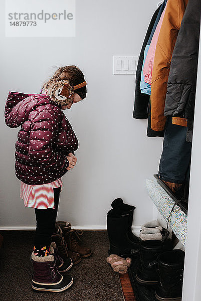 Mädchen zieht Jacke in der Garderobe an