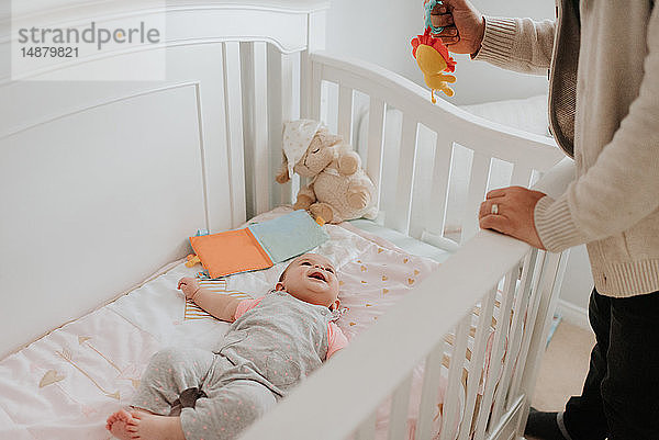 Vater bringt Baby-Tochter im Kinderbettchen ins Bett