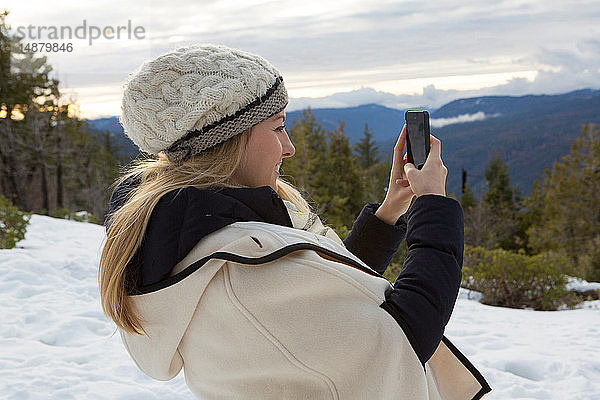 Junge Frau beim Smartphone-Selfie im Winterwald  Twain Harte  Kalifornien  USA