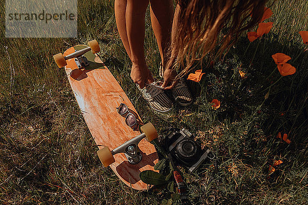 Junge Skateboardfahrerin beim Schnürsenkelbinden im Gras  Jalama  Kalifornien  USA