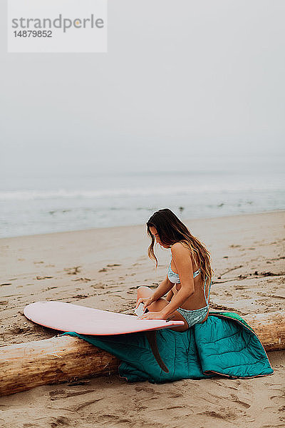 Junge Surferin sitzt auf einem Surfbrett mit Wachs am Strand  Ventura  Kalifornien  USA