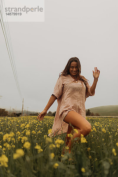 Junge Frau tanzt im gelben Wildblumenfeld  Jalama  Kalifornien  USA