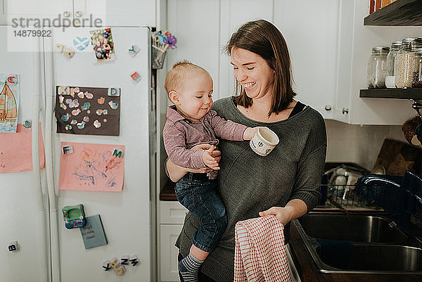 Mutter mit Säugling Sohn trocknet Geschirr in der Küche