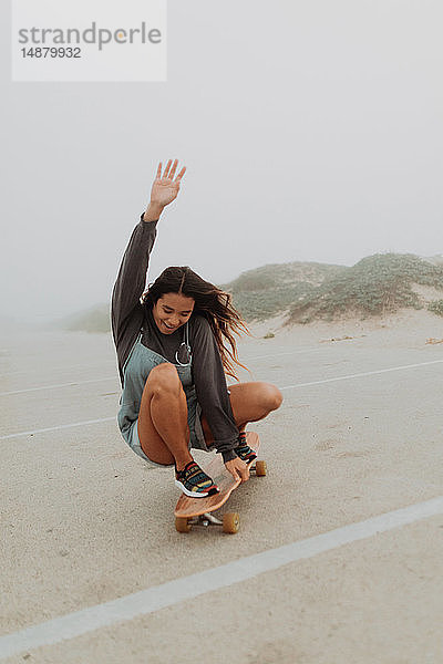 Junge Frau fährt Skateboard auf einem Parkplatz am nebligen Strand  Jalama  Kalifornien  USA