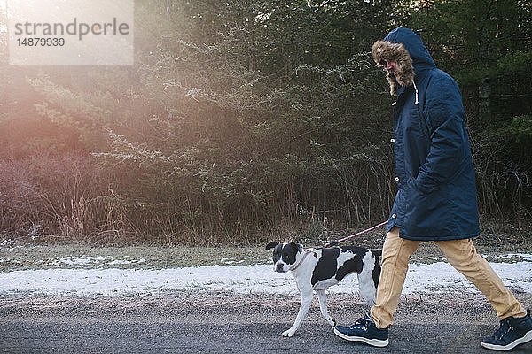 Mann geht mit Hund auf dem Land spazieren