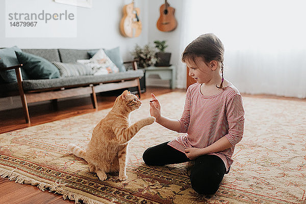 Mädchen spielt zu Hause mit Katze