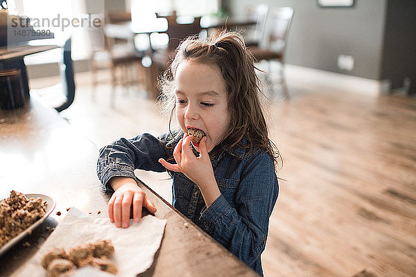 Kleines Mädchen isst frisch gebackene vegetarische Saatkugel