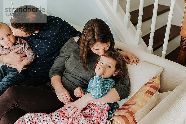 Mittelgroßes erwachsenes Paar auf dem Sofa mit Baby-Sohn und Kleinkind-Tochter