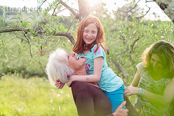 Mädchen wird von Großmutter getragen  mit Mutter im Garten