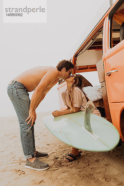 Junges surfendes Paar küsst sich am Strand mit einem Wohnmobil  Jalama  Ventura  Kalifornien  USA