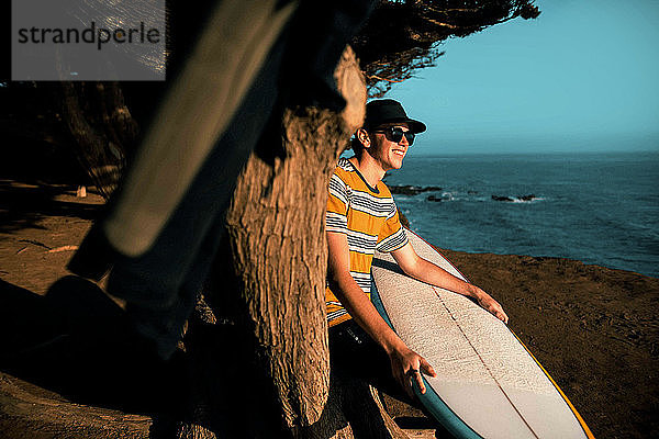 Junger Mann mit Surfbrett am Strand  Morro Bay  Kalifornien  Vereinigte Staaten