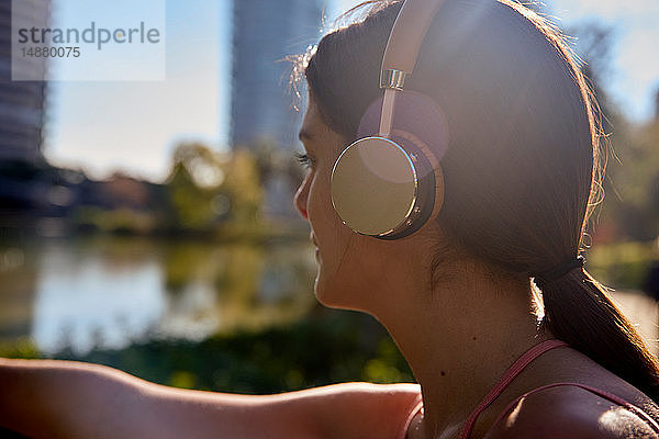 Frau  die im Stadtpark mit Kopfhörern Musik hört