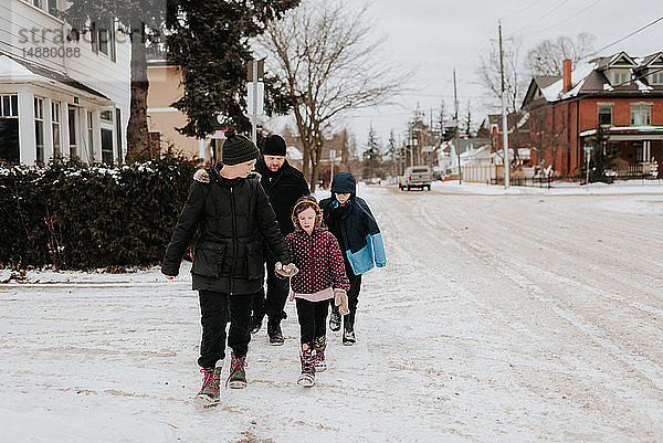 Eltern und Kinder laufen auf schneebedeckter Straße