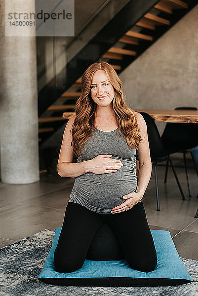 Schwangere Frau auf Yogamatte zu Hause