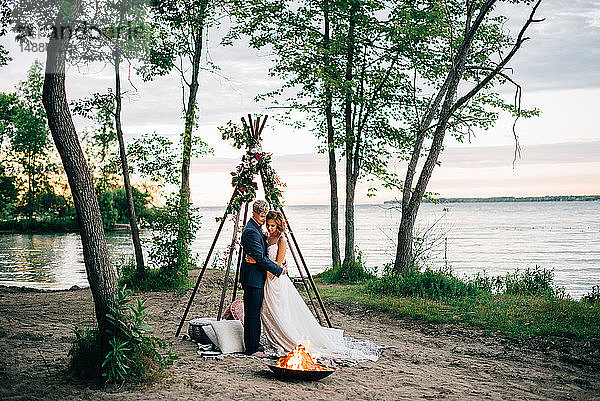 Braut und Bräutigam beim Blick auf das Lagerfeuer am Seeufer  Lake Ontario  Toronto  Kanada
