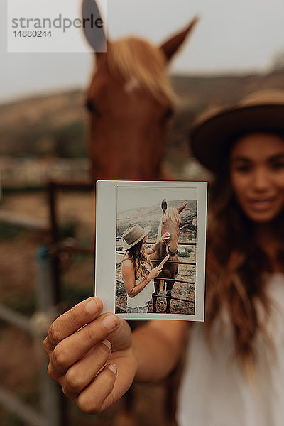 Junge Frau vor Pferd  die ein Sofortbild hochhält  Porträt  Jalama  Kalifornien  USA