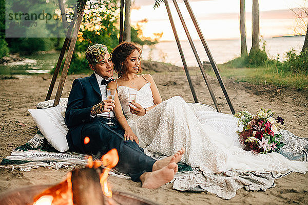 Braut und Bräutigam auf einer Picknickdecke am Lagerfeuer am Seeufer  Lake Ontario  Toronto  Kanada