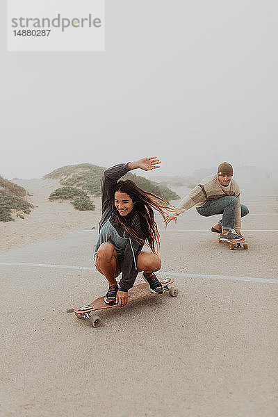 Junges Paar fährt Skateboard auf einem Parkplatz am nebligen Strand  Jalama  Kalifornien  USA