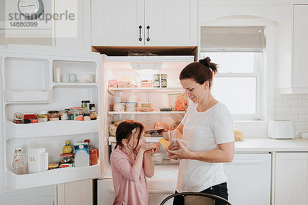 Mutter gibt Tochter Wurst aus dem Kühlschrank