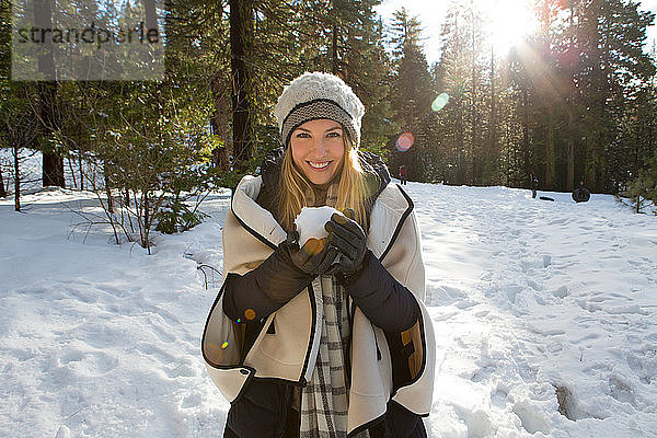 Junge Frau hält Schneeball im Winterwald  Porträt  Twain Harte  Kalifornien  USA
