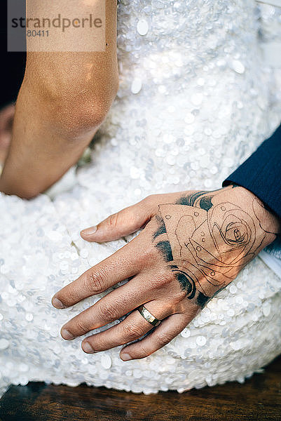 Tätowierte Hand des Bräutigams auf der Hüfte der Braut  Mittelteil
