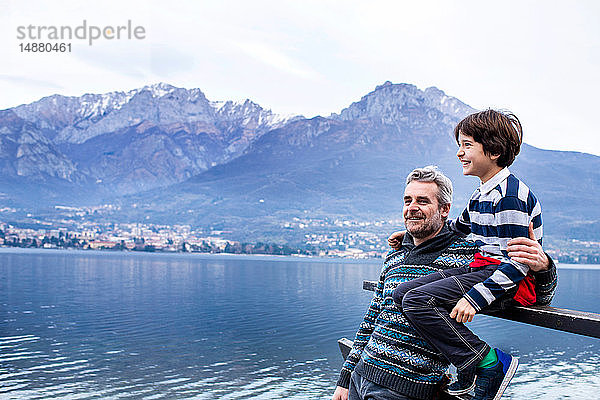 Junge und Vater sitzen am Comer See am Pierzaun. Onno  Lombardei  Italien