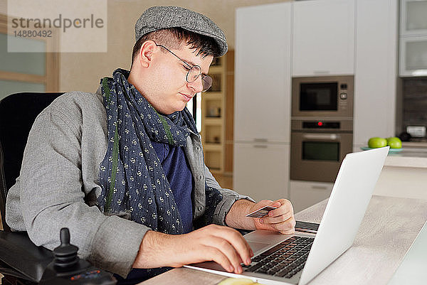 Körperlich behinderter Mann macht Online-Einkauf am Laptop zu Hause