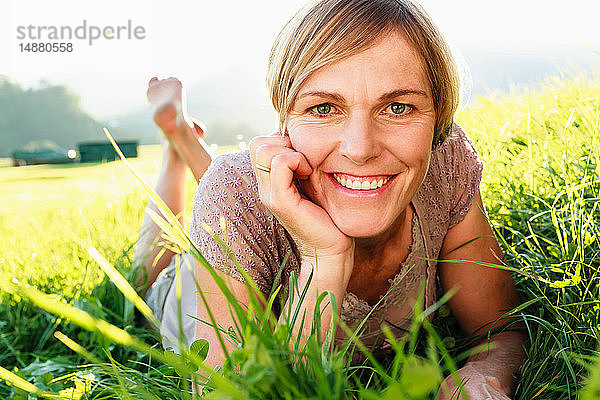 Frau liegt im Gras auf dem Land