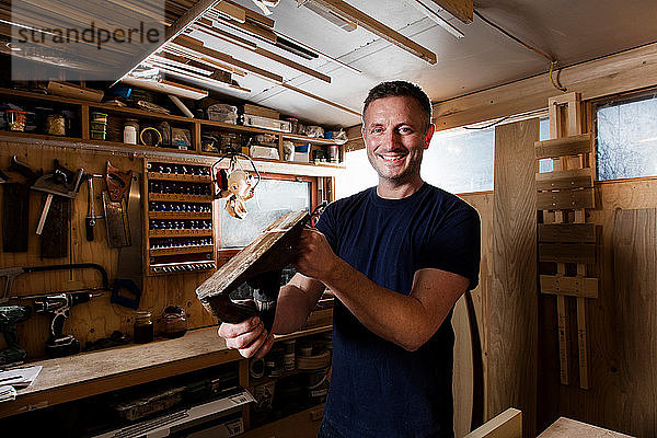 Handwerker hält Holzhobel in der Werkstatt