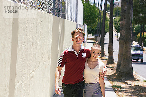 Junger Mann und Freundin spazieren auf dem Bürgersteig eines Vororts  Los Angeles  Kalifornien  USA