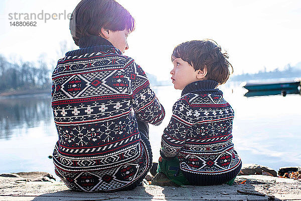 Junge und kleiner Bruder im passenden Pullover im Gespräch am Pier  Comer See  Lecco  Lombardei  Italien