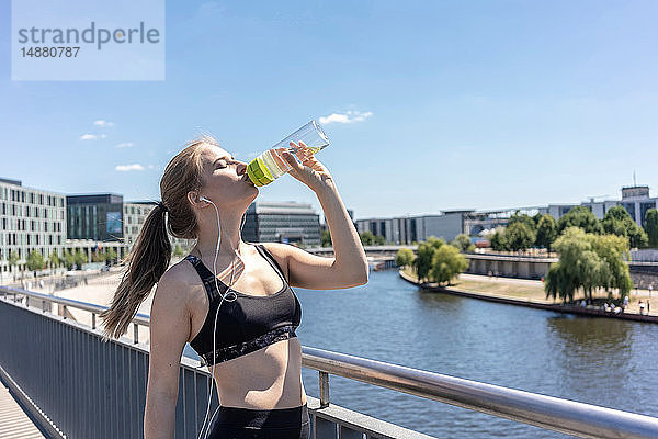 Junge Frau macht Pause von Sport und Trinkwasser in der Stadt  Berlin  Deutschland