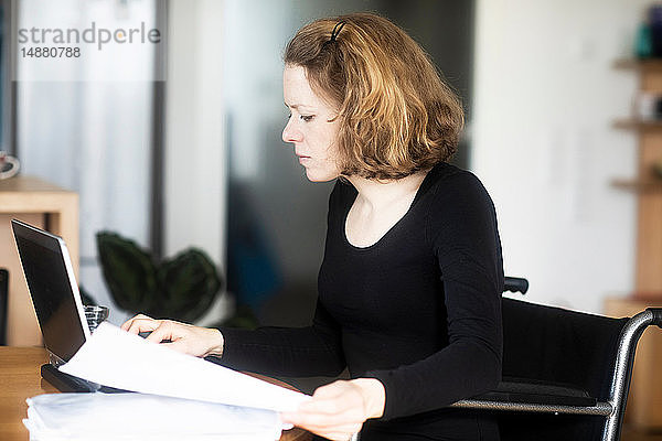 Frau im Rollstuhl bei der Arbeit am Laptop