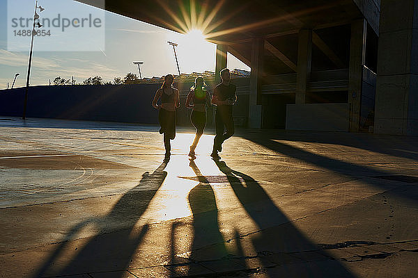 Freunde joggen bei Sonnenuntergang im Sportstadion