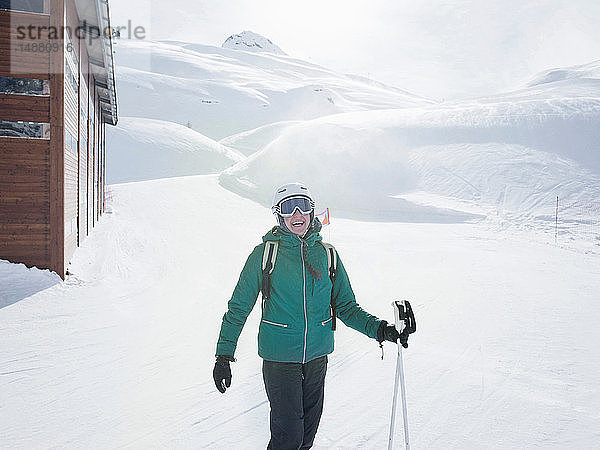 Junge Skifahrerin mit Helm und Skibrille lacht in schneebedeckter Landschaft  Porträt  Alpe Ciamporino  Piemont  Italien
