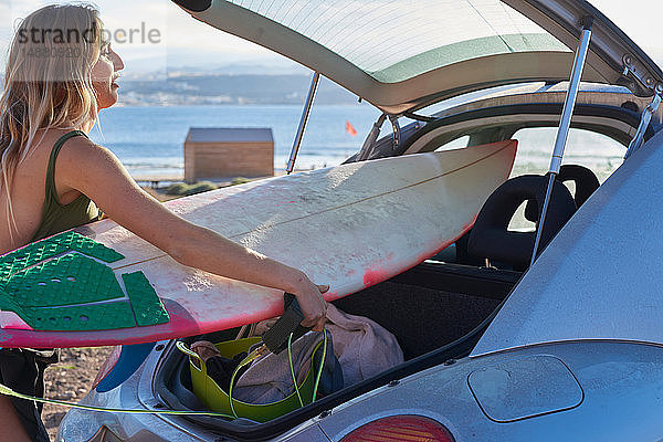 Junge Frau entfernt Surfbrett aus dem Kofferraum