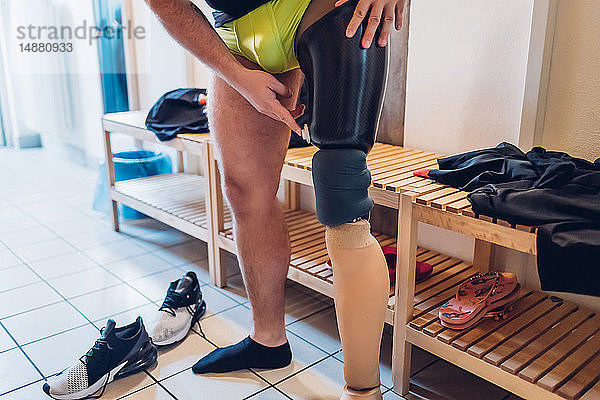 Mann mit Beinprothese im Umkleideraum der Turnhalle