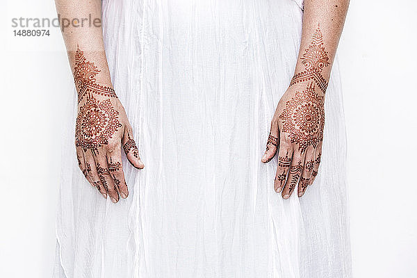 Frau in weißem Kleid mit Henna-Tattoo auf den Händen