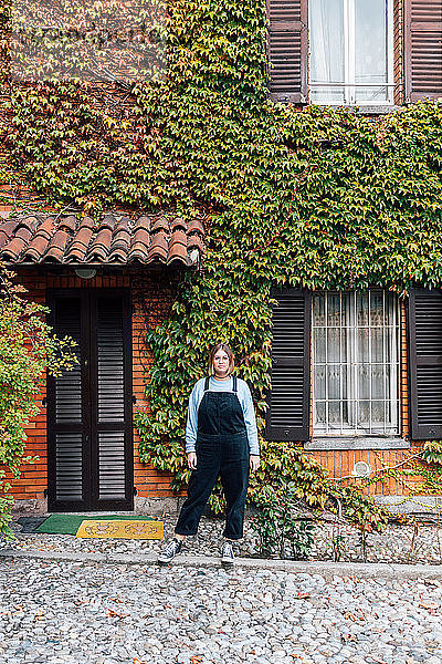 Frau vor Haus mit efeubewachsener Fassade  Rezzago  Lombardei  Italien